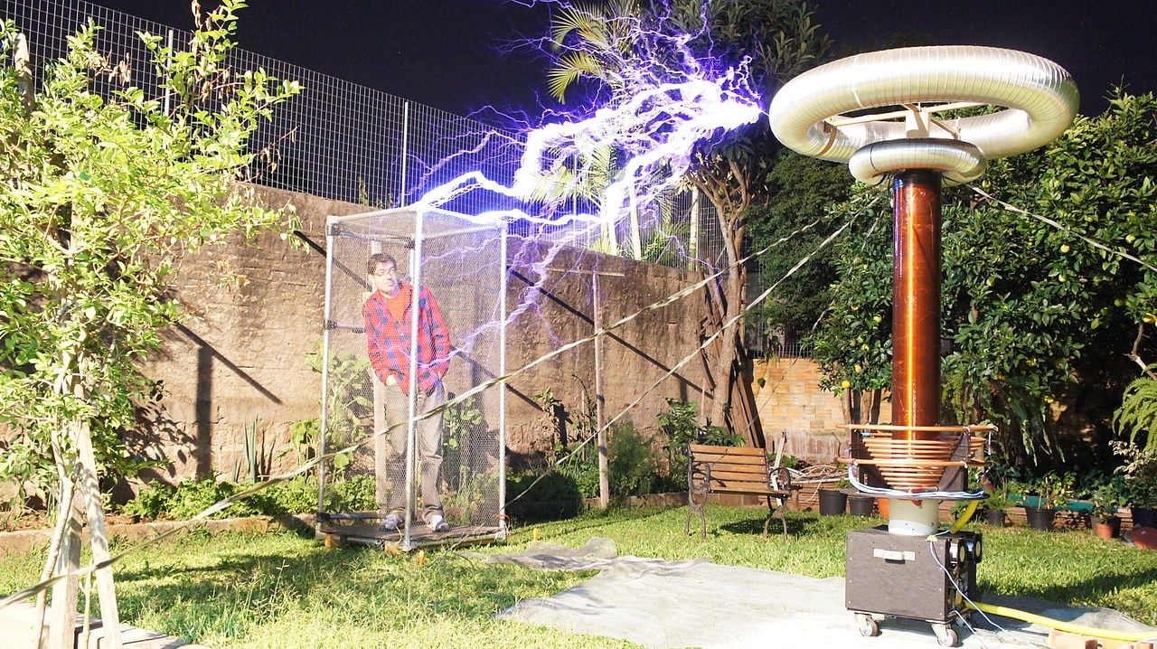 A Faraday cage with lightening bolt outside and man inside.