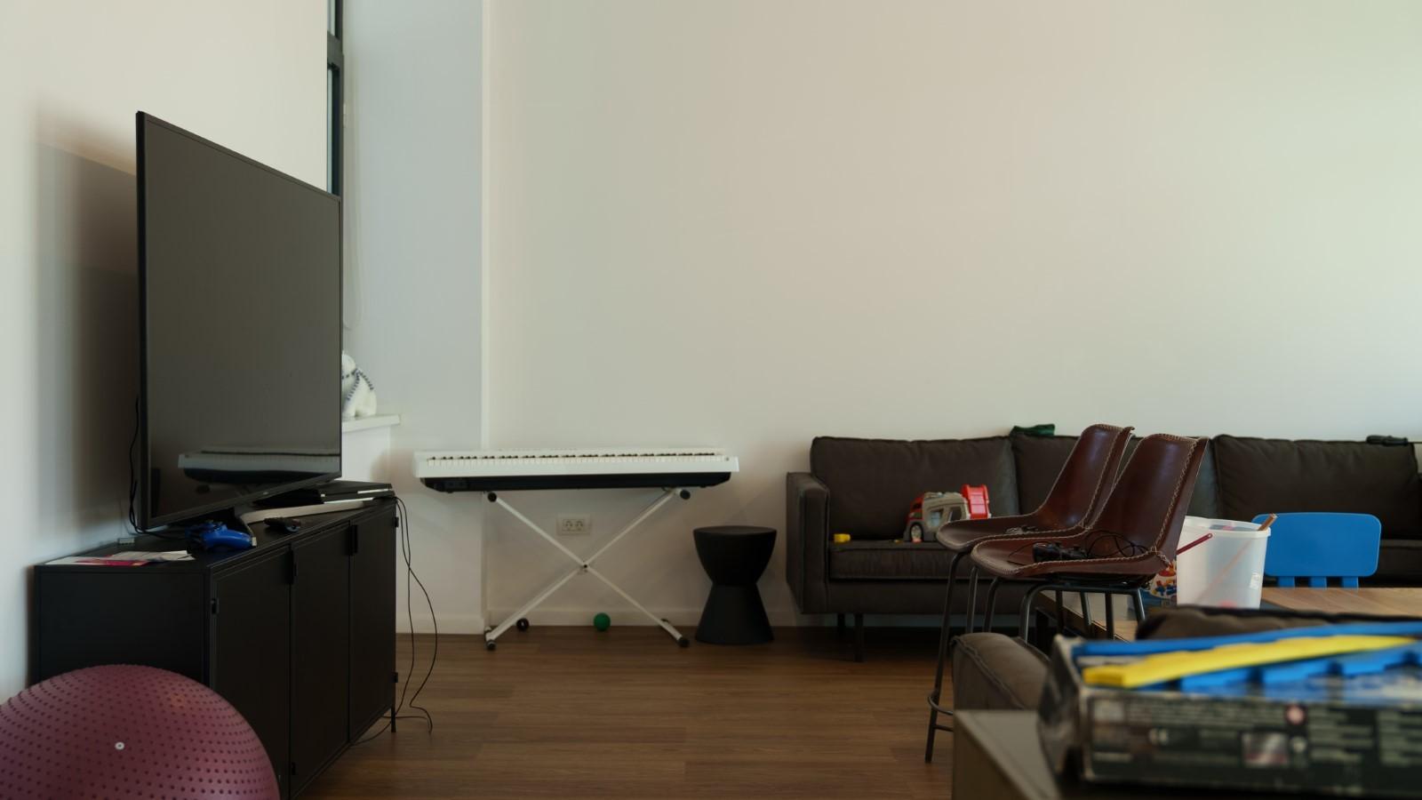 Picture of a space showing a TV, keyboard, couch, and table.