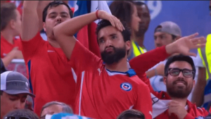 Chilean soccer fan doing a dance in front of a Chilean flag