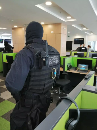 Police officer in full gear next to cubicles with green walls